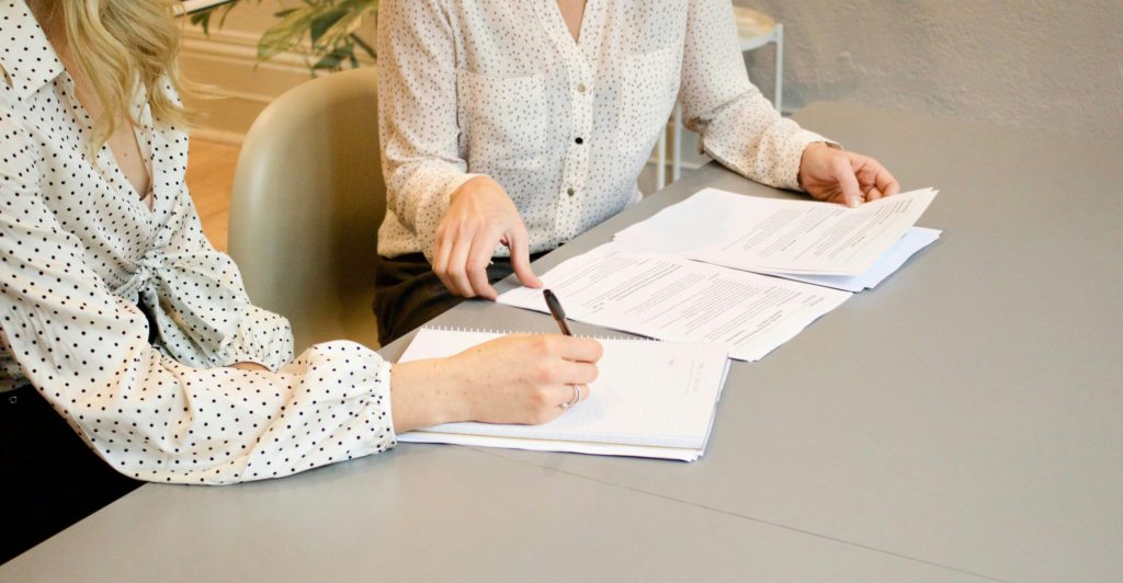 two women in business meeting writing on paper